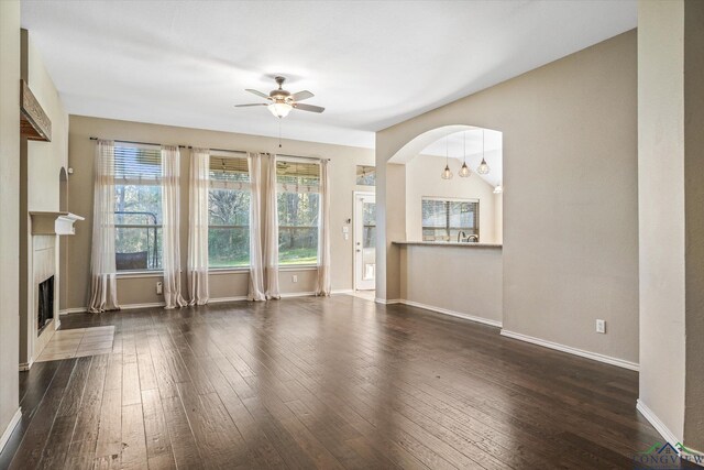 unfurnished living room with dark hardwood / wood-style floors, a fireplace, ceiling fan with notable chandelier, and vaulted ceiling