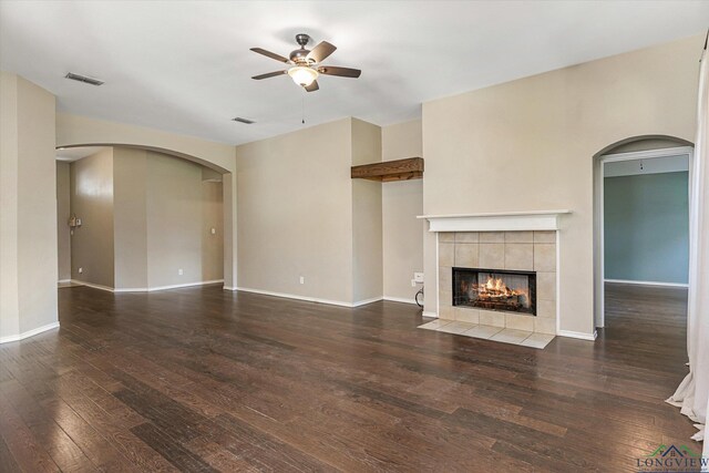 unfurnished living room featuring dark hardwood / wood-style floors, ceiling fan, and a tile fireplace