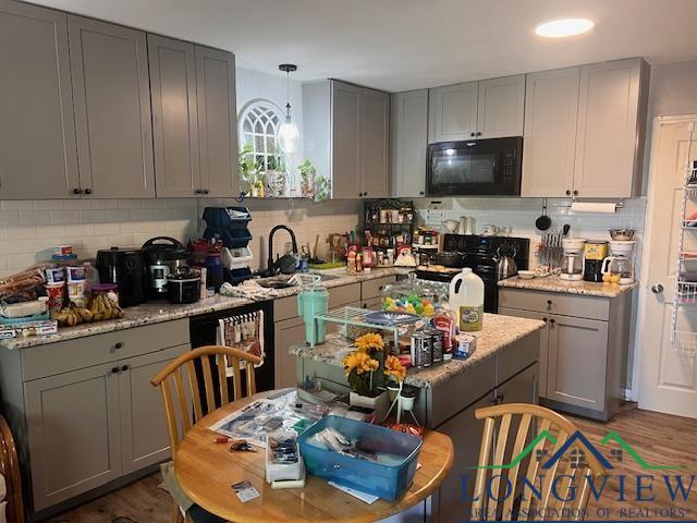 kitchen with black microwave, backsplash, stove, and gray cabinets