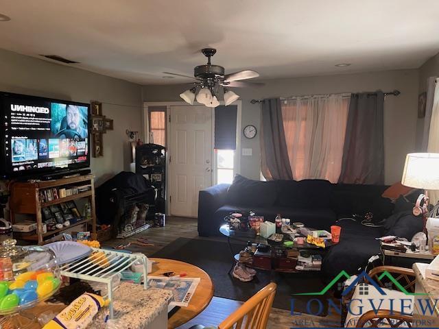 living room featuring wood finished floors, visible vents, and a ceiling fan