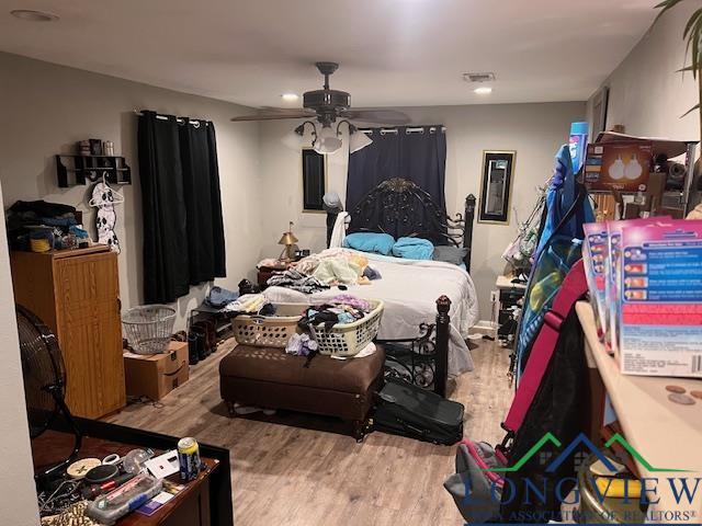 bedroom featuring wood finished floors, visible vents, and ceiling fan