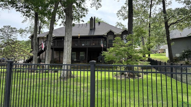 view of front facade with a fenced backyard, a chimney, a wooden deck, a shingled roof, and a front yard
