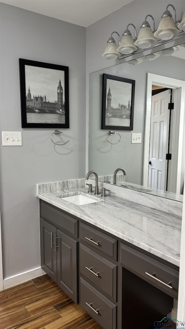 bathroom with baseboards, wood finished floors, and vanity