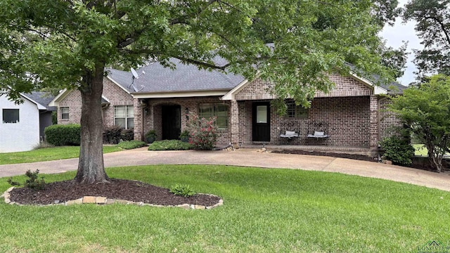single story home with a shingled roof, brick siding, and a front yard