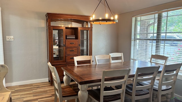 dining room with lofted ceiling, wood finished floors, a textured wall, baseboards, and a chandelier