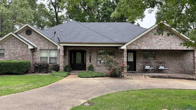 view of front of house with brick siding, a shingled roof, and a front yard