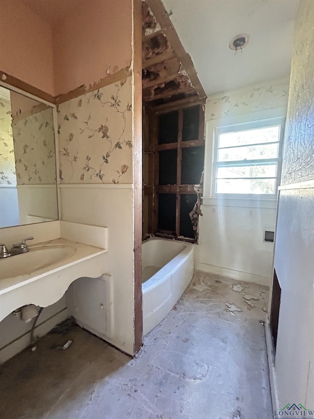 bathroom featuring a washtub, concrete flooring, and sink