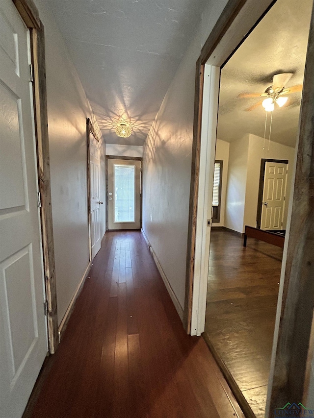 corridor with dark hardwood / wood-style flooring and lofted ceiling