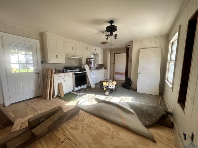 kitchen with white gas stove, a healthy amount of sunlight, white cabinetry, and ceiling fan