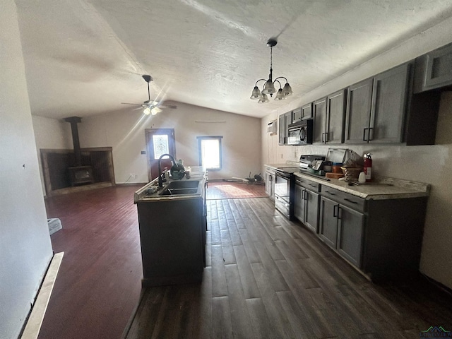 kitchen with pendant lighting, stainless steel electric range, a wood stove, lofted ceiling, and sink