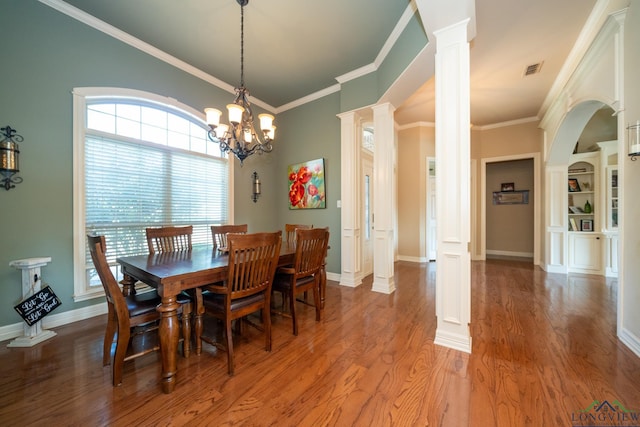 dining room featuring wood-type flooring, decorative columns, an inviting chandelier, and crown molding