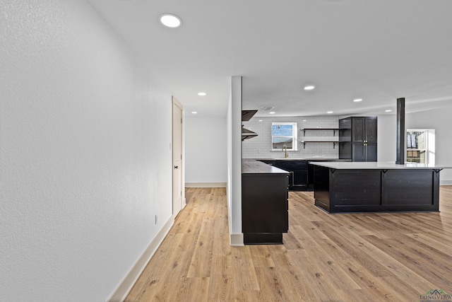 kitchen with a center island, a healthy amount of sunlight, light hardwood / wood-style flooring, backsplash, and a breakfast bar