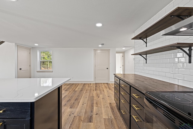 kitchen with backsplash, a kitchen island, light hardwood / wood-style floors, and stainless steel range with electric cooktop