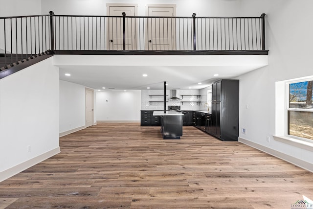 unfurnished living room with light wood-type flooring, sink, and a high ceiling