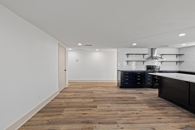 kitchen featuring hardwood / wood-style floors, wall chimney range hood, backsplash, and stainless steel electric range oven