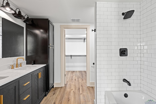 bathroom featuring hardwood / wood-style floors, vanity, and tiled shower / bath