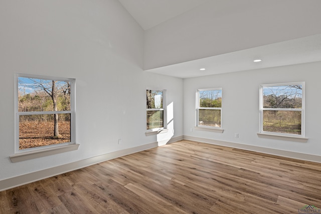 unfurnished room with light wood-type flooring and high vaulted ceiling