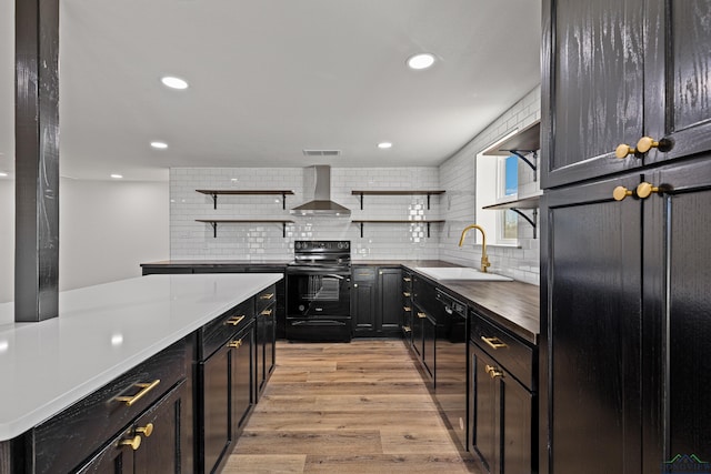 kitchen featuring black appliances, sink, wall chimney exhaust hood, light wood-type flooring, and tasteful backsplash