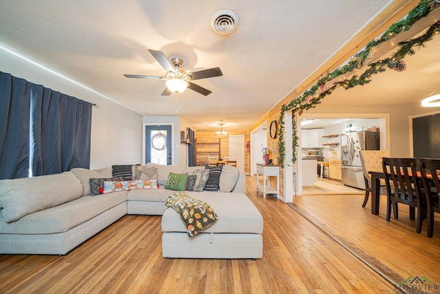 living room featuring ceiling fan, a textured ceiling, and light hardwood / wood-style flooring