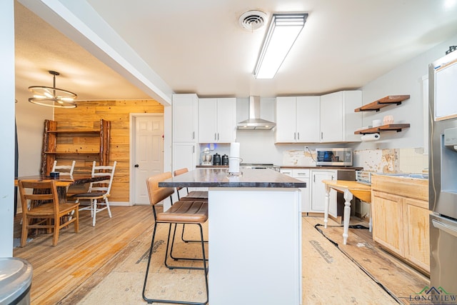 kitchen with tasteful backsplash, a notable chandelier, wall chimney exhaust hood, white cabinets, and a center island