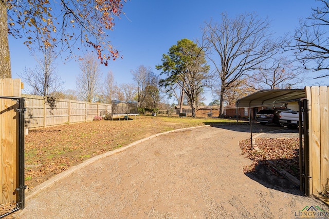 view of yard with a trampoline and a carport