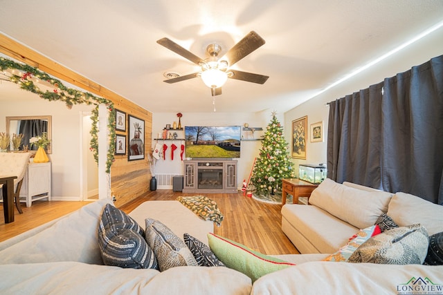 living room featuring ceiling fan, light hardwood / wood-style flooring, and a fireplace