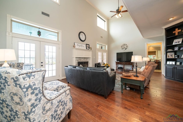 335 Winding Way, Hallsville, TX 75650 - living area featuring ceiling fan, a high ceiling, dark wood-style flooring, a fireplace, and french doors