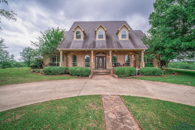 335 Winding Way, Hallsville, TX 75650 - cape cod-style house featuring brick siding, covered porch, a front lawn, and a shingled roof