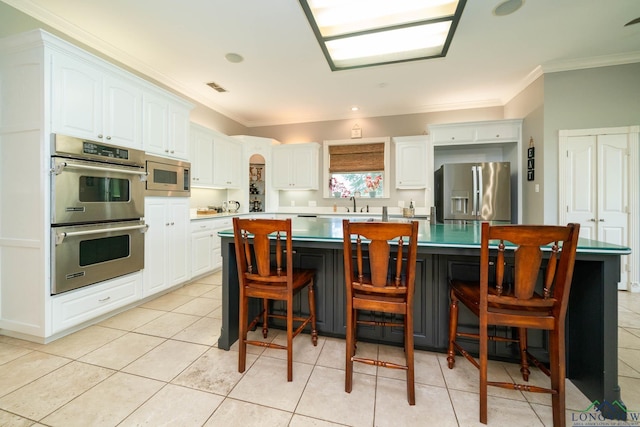 335 Winding Way, Hallsville, TX 75650 - kitchen with appliances with stainless steel finishes, crown molding, white cabinets, a spacious island, and a kitchen bar