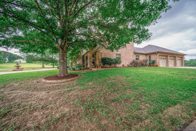 335 Winding Way, Hallsville, TX 75650 - obstructed view of property featuring a front lawn, an attached garage, brick siding, and driveway