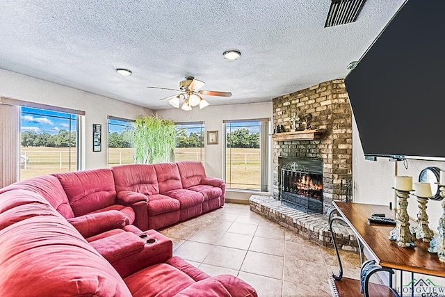 living room featuring a wealth of natural light, a fireplace, light tile patterned floors, and ceiling fan