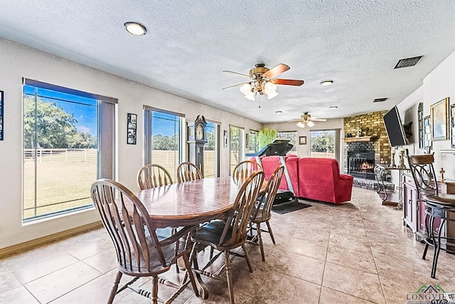 dining room with plenty of natural light, light tile patterned floors, and a brick fireplace