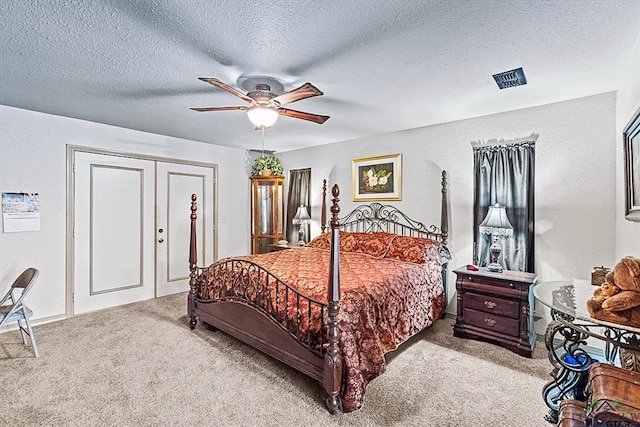 bedroom featuring a textured ceiling, light colored carpet, and ceiling fan