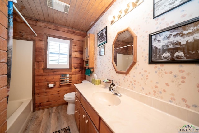 bathroom featuring wood finished floors, wallpapered walls, vanity, toilet, and visible vents