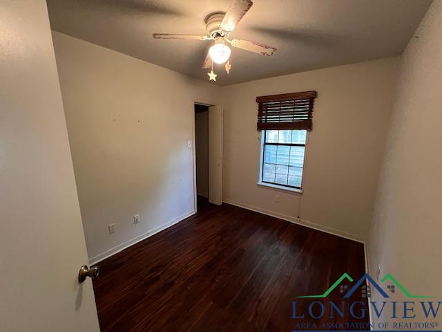 spare room featuring ceiling fan and dark wood-type flooring