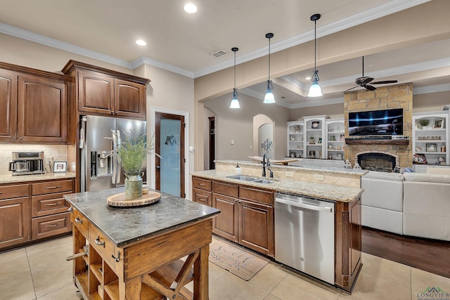 kitchen featuring sink, hanging light fixtures, stainless steel appliances, an island with sink, and light tile patterned flooring