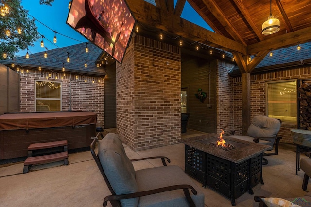 patio terrace at dusk featuring a hot tub and a fire pit