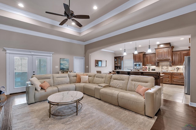 living room with ceiling fan, french doors, crown molding, and light wood-type flooring