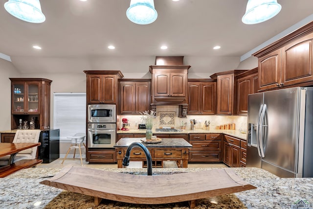 kitchen featuring pendant lighting, light stone countertops, and appliances with stainless steel finishes