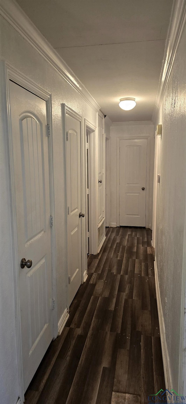 hall with ornamental molding, dark wood-type flooring, and a textured wall