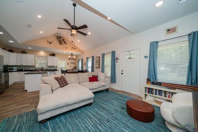 living room with high vaulted ceiling, recessed lighting, ceiling fan with notable chandelier, visible vents, and dark wood-style floors