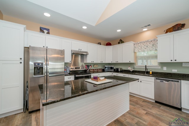 kitchen featuring visible vents, stainless steel appliances, under cabinet range hood, white cabinetry, and a sink