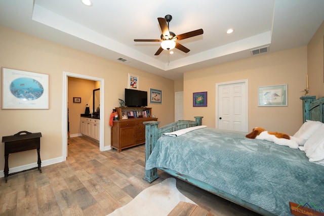 bedroom with light wood-style flooring, a raised ceiling, visible vents, and recessed lighting