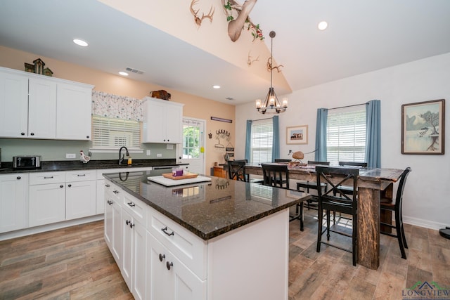 kitchen featuring light wood-style flooring, recessed lighting, a sink, white cabinets, and a center island