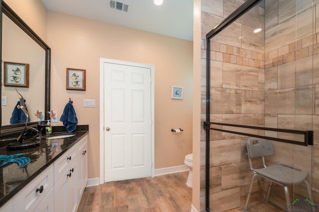 full bathroom with visible vents, toilet, a stall shower, vanity, and wood finished floors