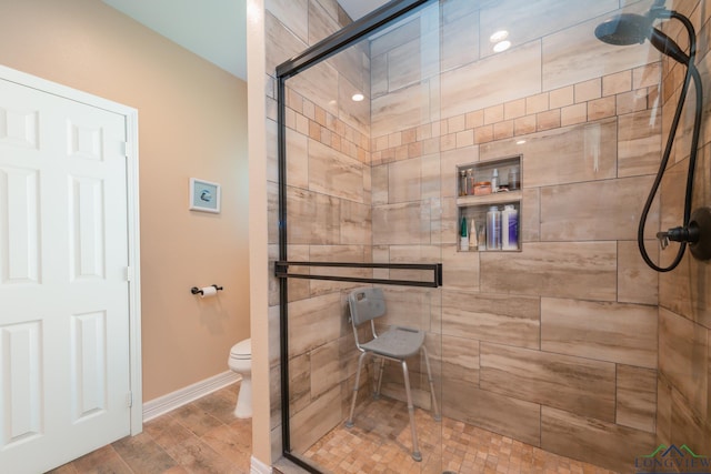 bathroom with toilet, a stall shower, baseboards, and wood finished floors