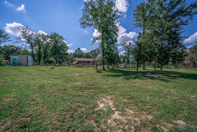 view of yard featuring an outbuilding, fence, and an outdoor structure