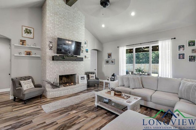 living room with high vaulted ceiling, a brick fireplace, ceiling fan, beamed ceiling, and wood-type flooring