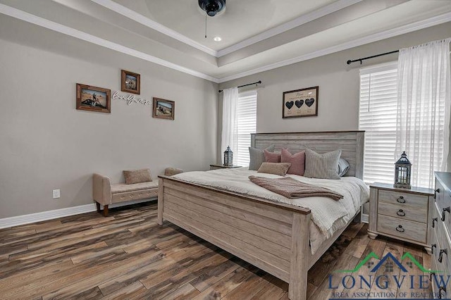 bedroom featuring dark hardwood / wood-style floors, ceiling fan, ornamental molding, and a tray ceiling