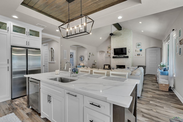 kitchen featuring an island with sink, sink, white cabinets, and stainless steel appliances